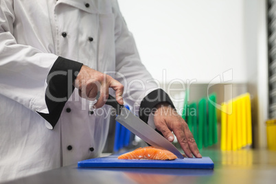 Chef cutting salmon with sharp knife