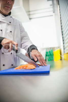 Chef cutting raw salmon with sharp knife