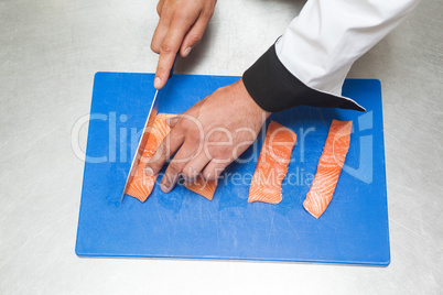 Chef slicing raw salmon with sharp knife