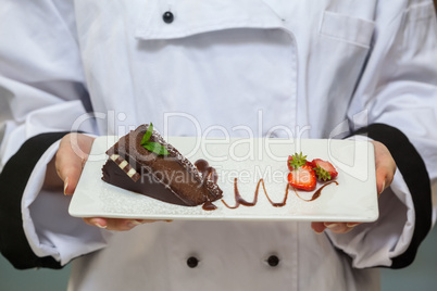 Chef presenting chocolate cake with strawberries