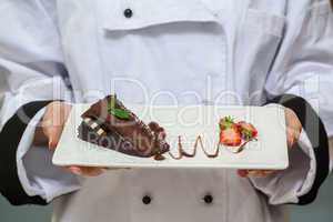 Chef presenting chocolate cake with strawberries