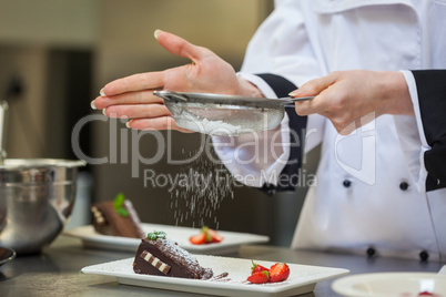 Female chef finishing a dessert plate