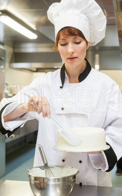 Pretty focused head chef finishing a cake with icing