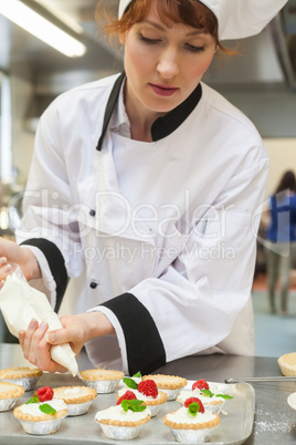 Pretty concentrating head chef preparing dessert