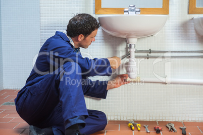 Handsome plumber repairing sink