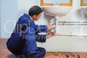 Handsome plumber repairing sink