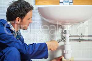 Handsome happy plumber repairing sink