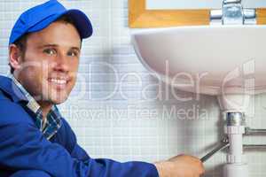 Attractive cheerful plumber repairing sink
