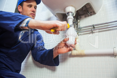 Frowning plumber repairing sink