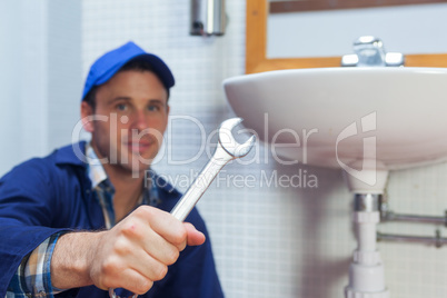Handsome smiling plumber showing wrench