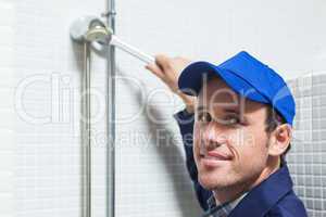 Cheerful plumber repairing shower head