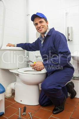 Good looking plumber repairing toilet