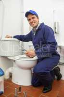 Good looking plumber repairing toilet