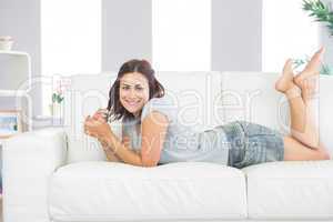 Portrait of pretty brunette woman lying on her couch in the livi