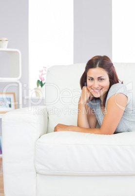 Gorgeous young woman lying on her white couch