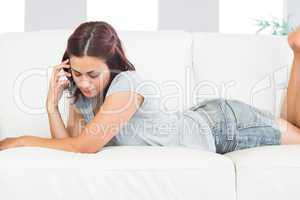 Young brunette woman lying on her couch at home