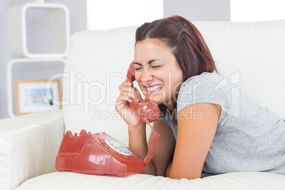 Gorgeous amused woman using a dial phone
