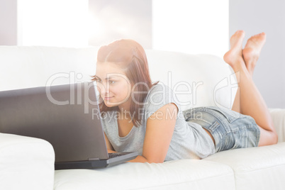 Content brunette woman lying on her white couch