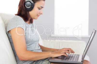 Casual woman working with her notebook and listening to music