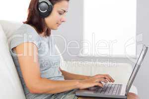 Casual woman working with her notebook and listening to music
