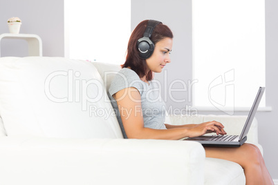 Focused attractive woman using her notebook and listening to mus
