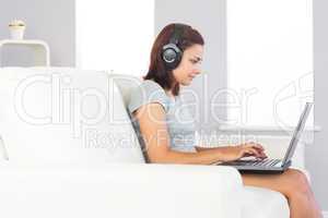 Focused attractive woman using her notebook and listening to mus