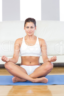 Pretty sporty woman in sportswear sitting on an exercise mat in