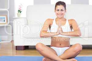 Cheerful young woman sitting in lotus position on a blue exercis