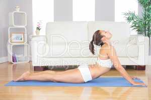 Slim brunette woman lying in yoga pose in her living room