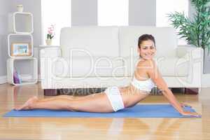 Smiling young woman stretching in a yoga pose on a blue exercise