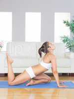 Pretty woman in sportswear doing yoga in her living room