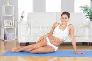 Young sporty woman posing sitting on an exercise mat