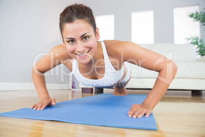 Portrait of fit woman practicing press ups in her living room