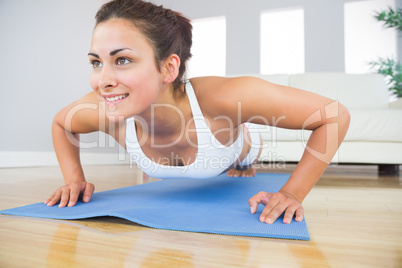 Young fit woman doing press ups on an exercise mat