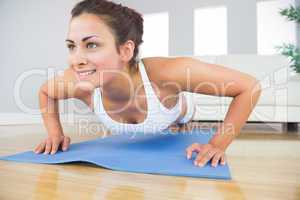 Young fit woman doing press ups on an exercise mat
