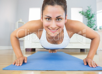 Fit young woman practicing press ups on a blue exercise mat