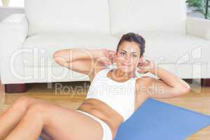 Portrait of fit calm woman doing sit ups on exercise mat