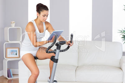 Concentrated slender woman training on an exercise bike while us