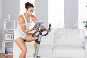 Concentrated slender woman training on an exercise bike while us
