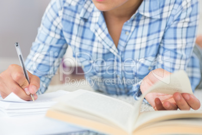 Mid section of young female student doing assignments while lyin
