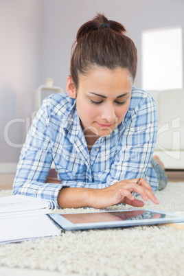 Cute brunette student working with her tablet while doing assign