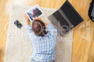 Young brunette woman lying on the floor using her tablet and not