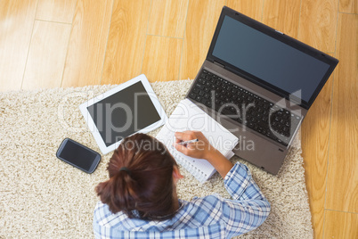 Brunette young student using her tablet and notebook for doing h