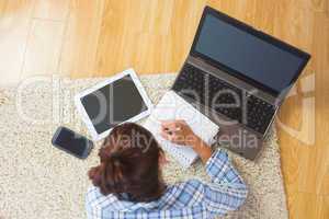Brunette young student using her tablet and notebook for doing h