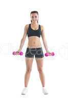 Slender brunette woman using dumbbells for training her arms