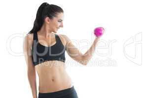 Cheerful slender woman training her arm using a pink dumbbell
