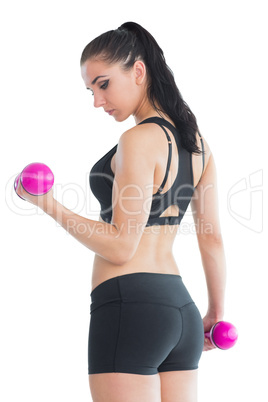 Beautiful fit woman training her arms with pink dumbbells