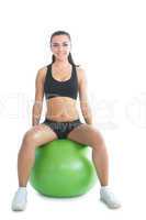 Front view of cute sporty woman sitting on an exercise ball
