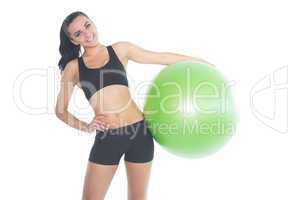 Attractive fit woman posing holding a green exercise ball