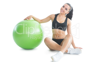 Cute slender woman posing sitting on the floor next to an exerci
